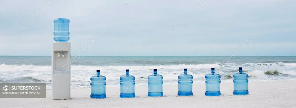 Water cooler and water jugs lined up on beach