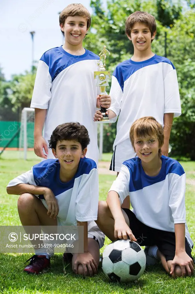 Young soccer teammates posing with trophy, portrait
