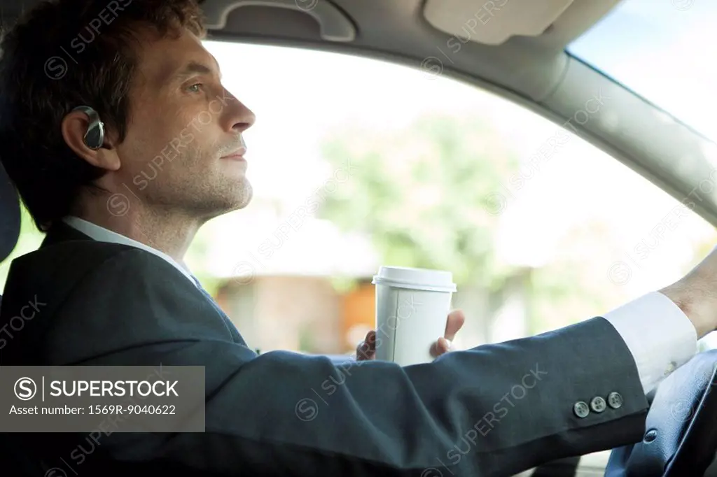 Businessman driving to work with cup of coffee in hand