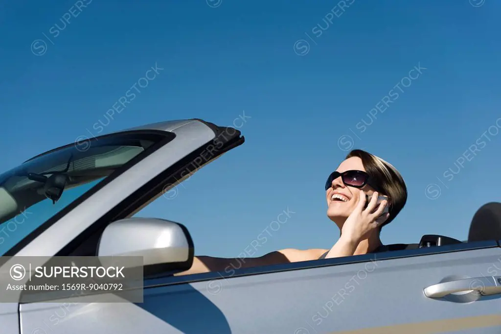 Woman talking on cell phone while driving convertible