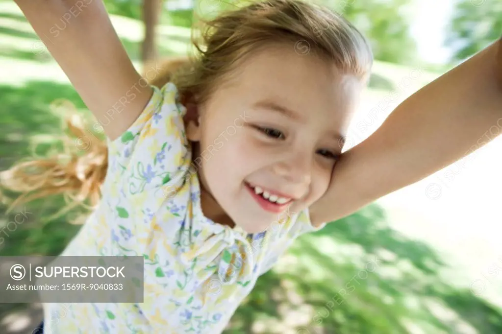 Little girl being spun by arms outdoors