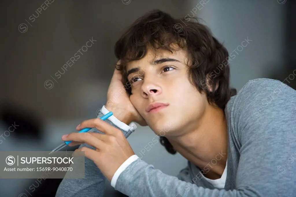 Young man leaning on elbow idly looking away