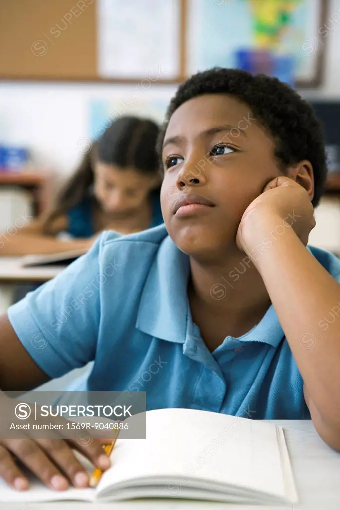Male elementary school student daydreaming in class