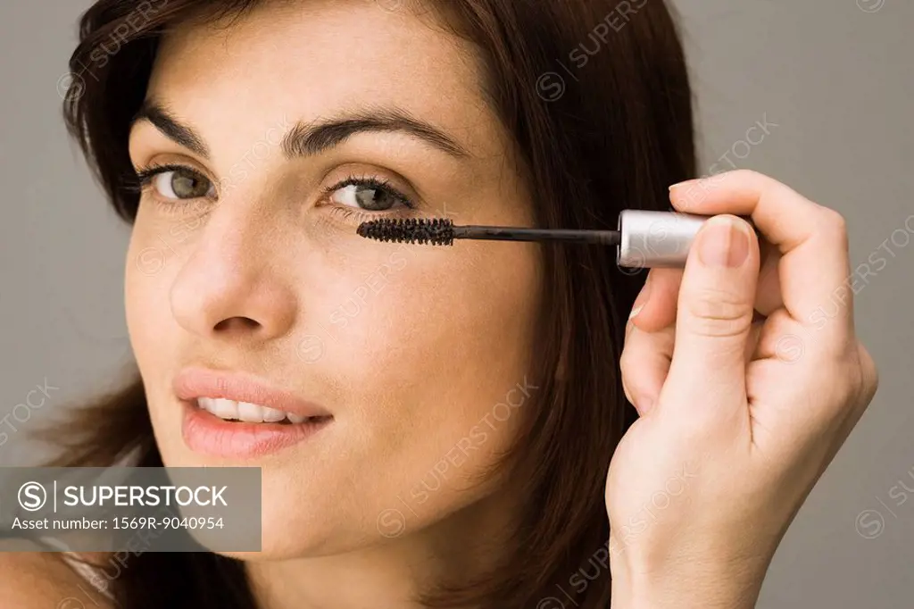 Young woman putting on mascara