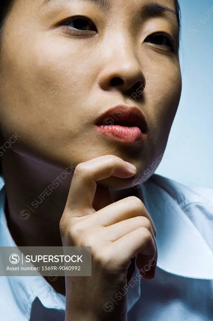 Young woman with hand under chin contemplatively looking away