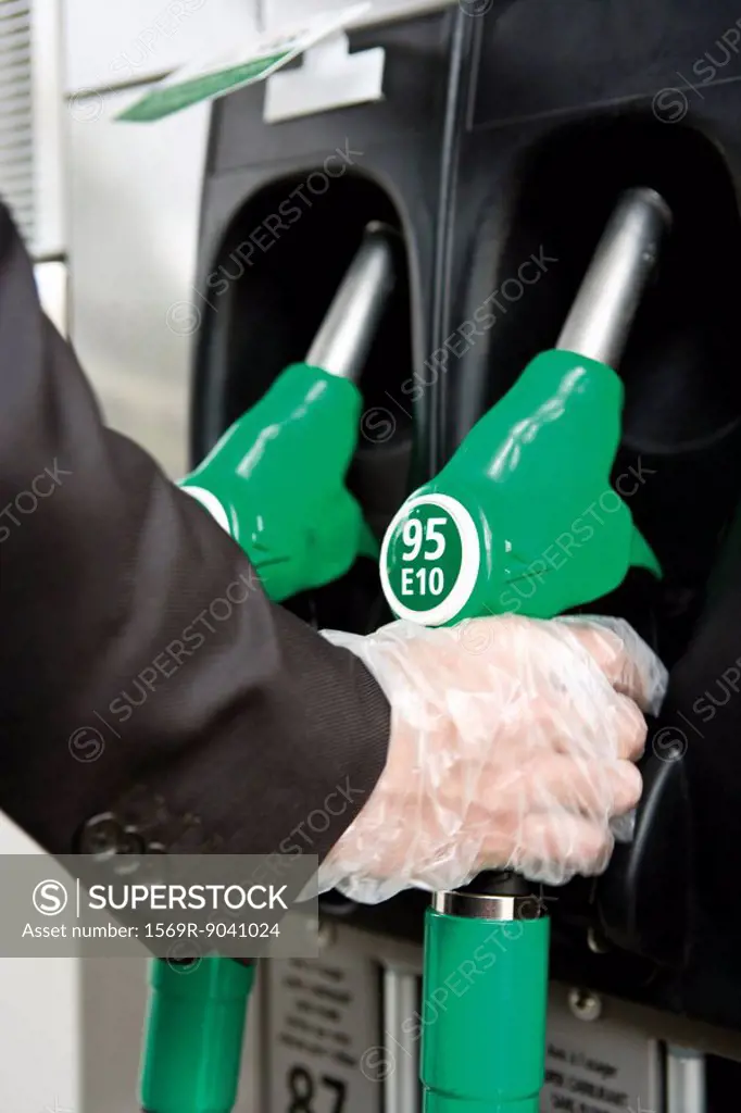At gas pump with gloved hand removing nozzle