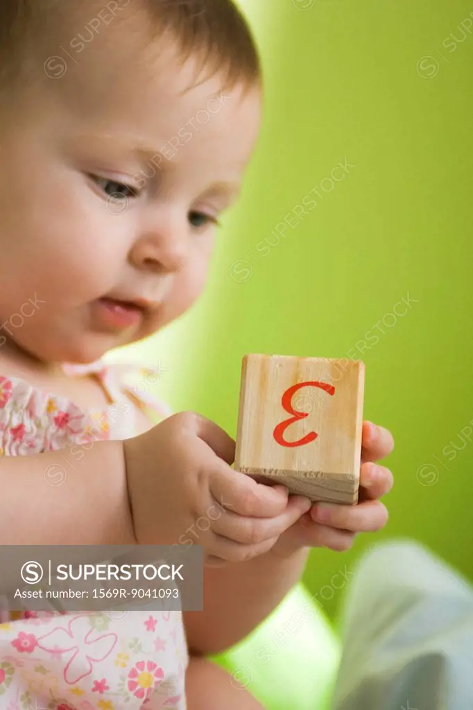 Infant girl holding wooden block