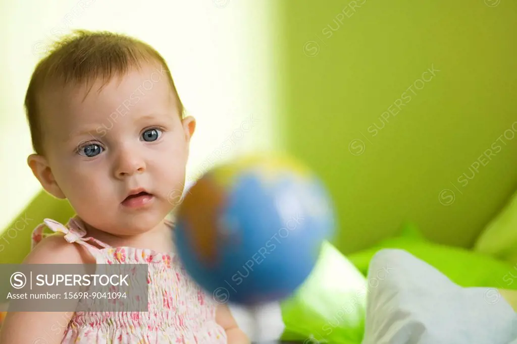 Infant girl contemplating toy globe