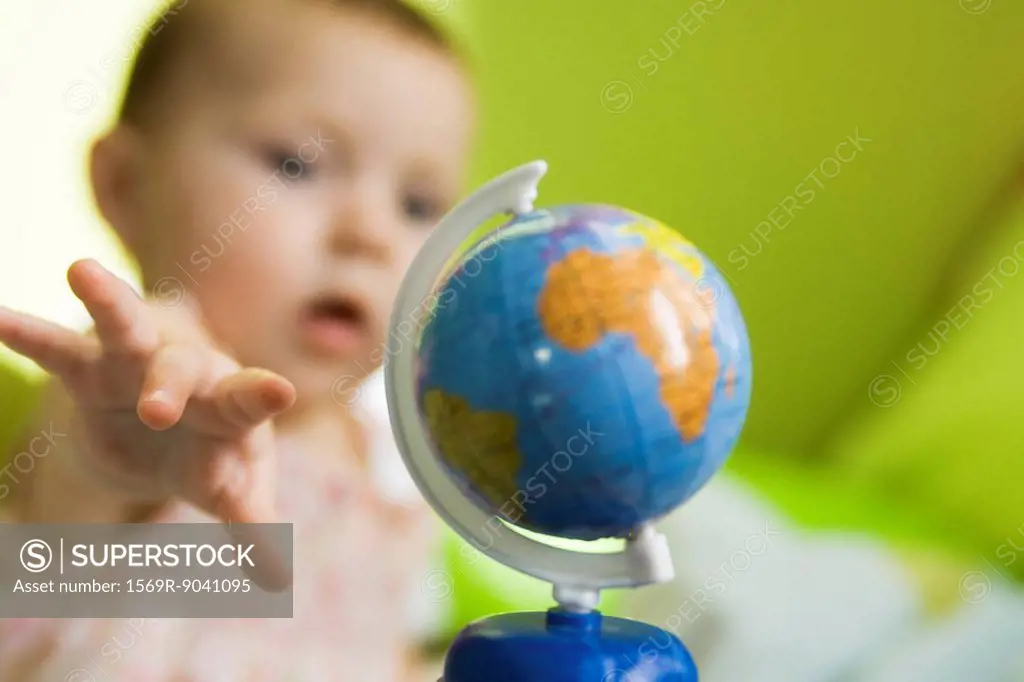 Infant girl reaching for toy globe