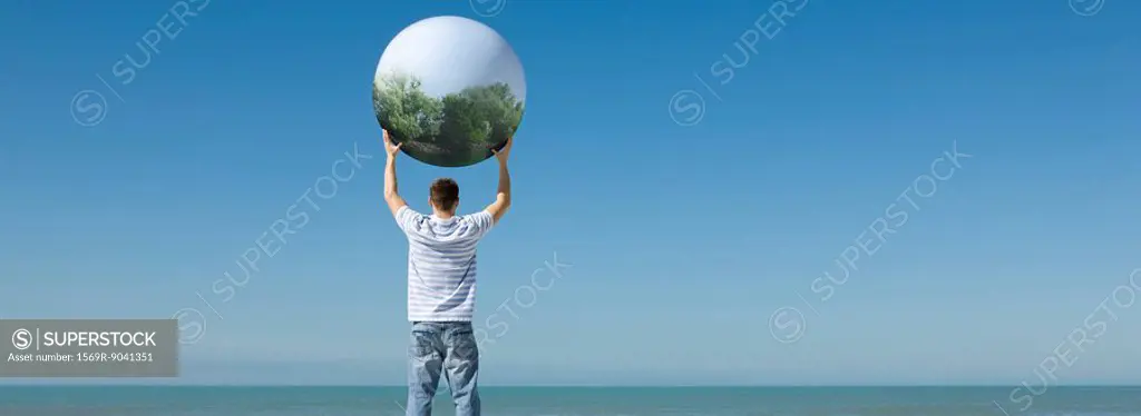 Holding aloft globe displaying image of trees