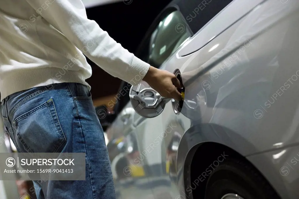 Driver opening gas tank to refuel at gas station