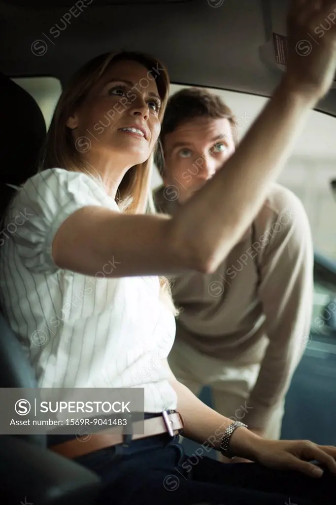 Couple checking out new car interior in dealership showroom