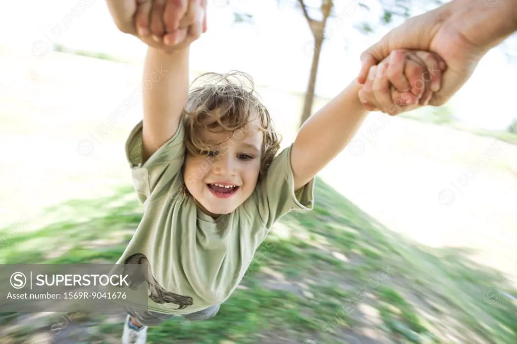 Boy being swung through air by his arms
