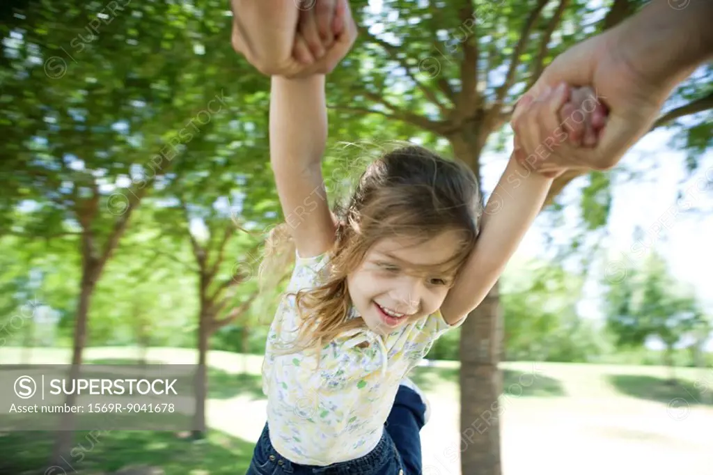 Little girl being swung through air by her arms