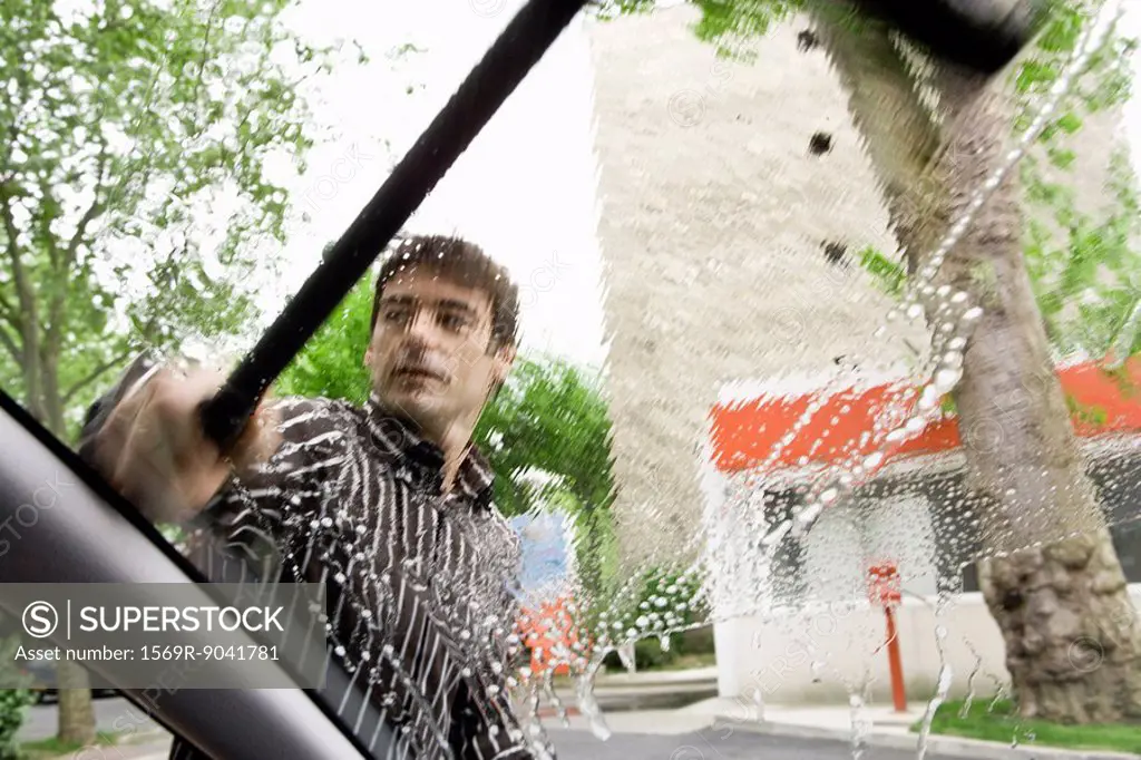Man washing car windshield with squeegee
