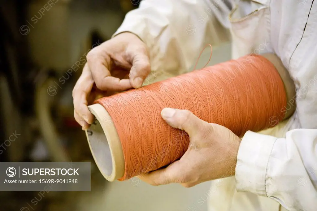 Recyclable composite textile fabrication department of factory, worker performing quality control on thread