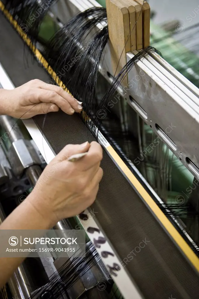 Fabric coating plant, weaving department, mechanist preparing weaver´s reed on loom