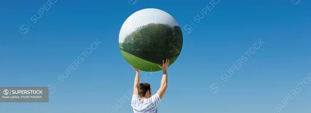 Holding aloft globe displaying image of forest