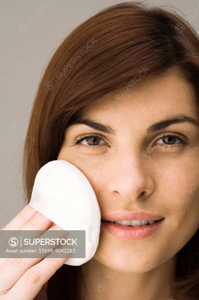 Young woman applying facial powder