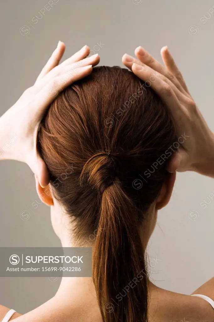 Woman styling hair, rear view