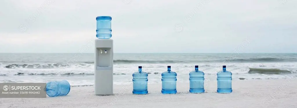 Water cooler and water jugs lined up on beach