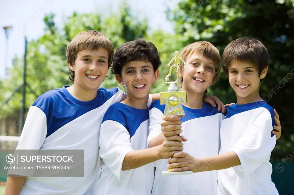 Young soccer teammates holding trophy together, portrait