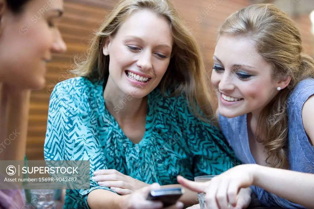 Young woman showing cell phone to friends