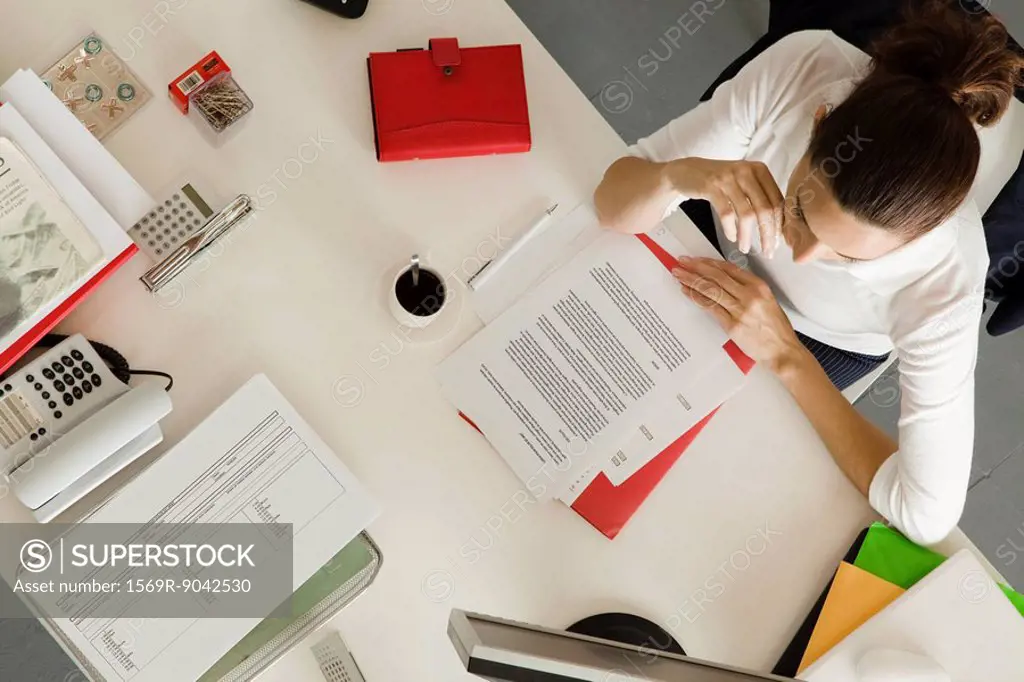 Businesswoman at desk busy with paperwork, overhead view