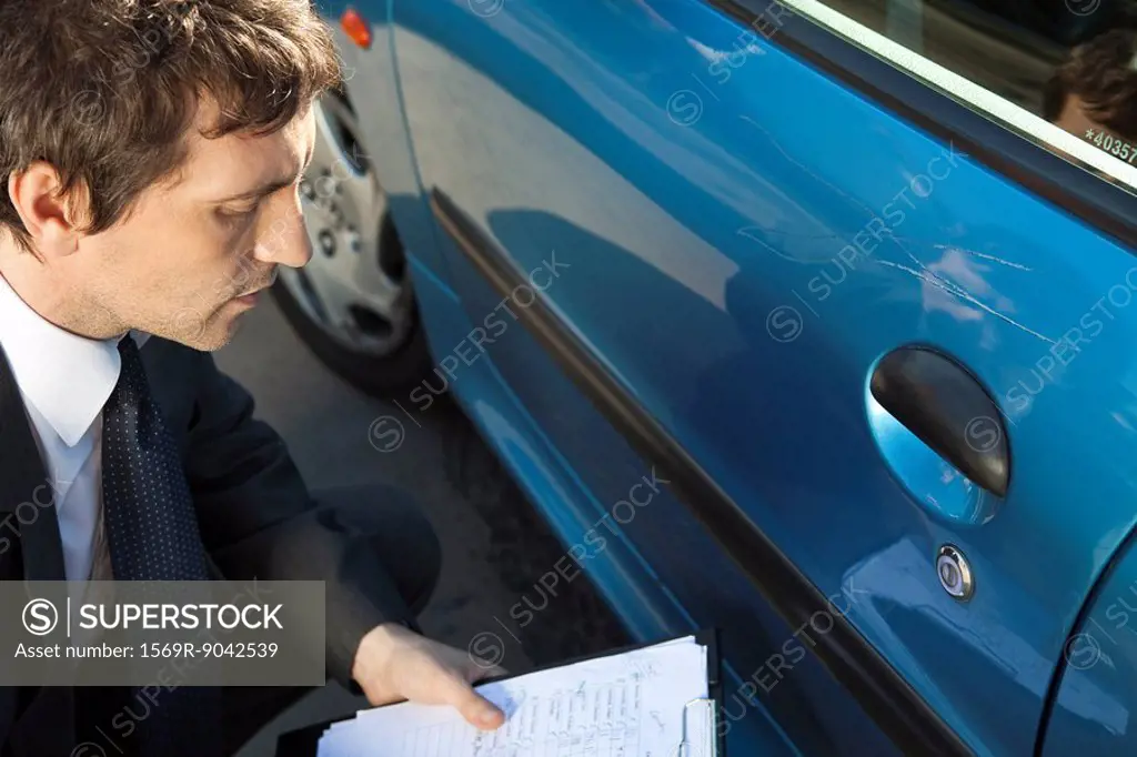 Insurance adjuster examining damage to car exterior
