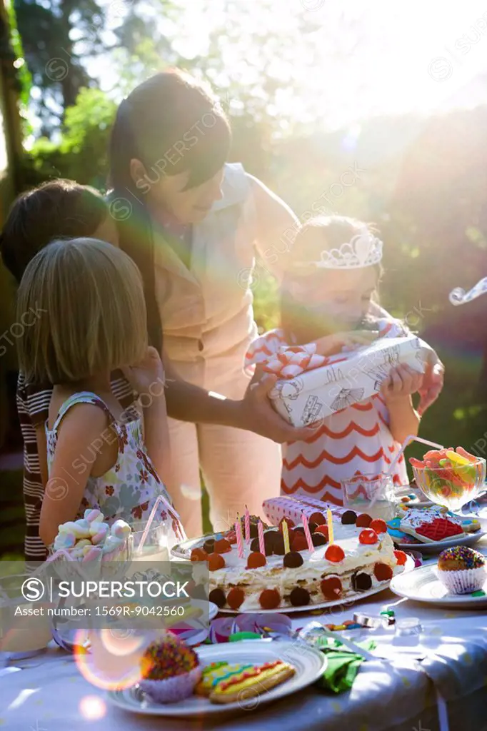 Girl opening gift at outdoor birthday party