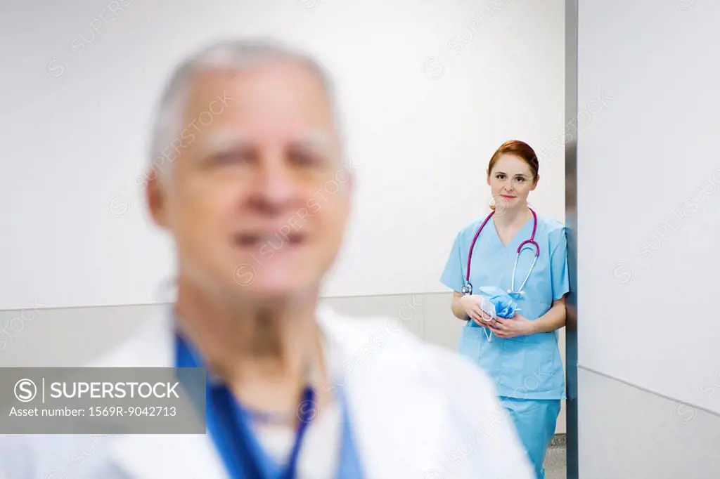 Nurse leaning against wall looking with admiration at doctor