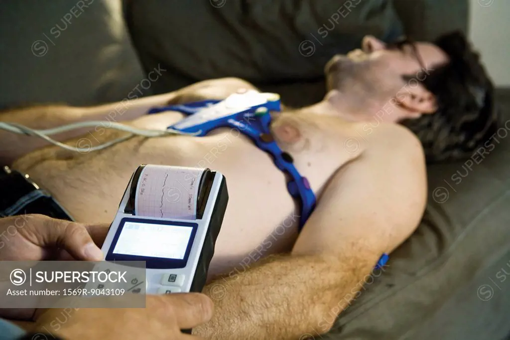 Doctor performing portable EKG electrocardiogram on patient in home