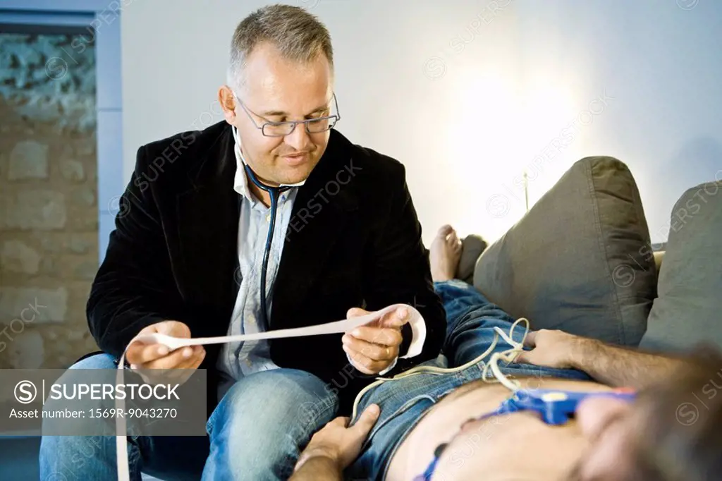 Doctor performing portable EKG electrocardiogram on patient in home
