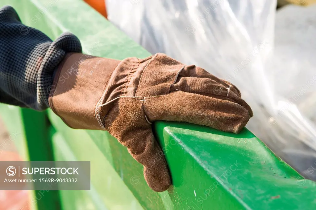 Gloved hand holding onto edge of dumpster