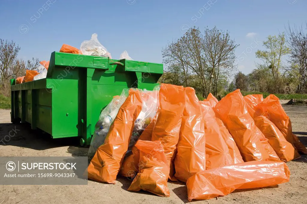 Garbage bags piled beside dumpster
