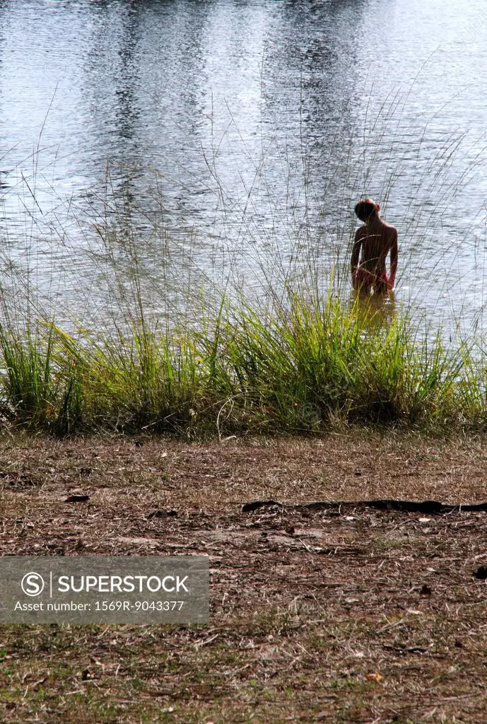 Child wading in lake, rear view
