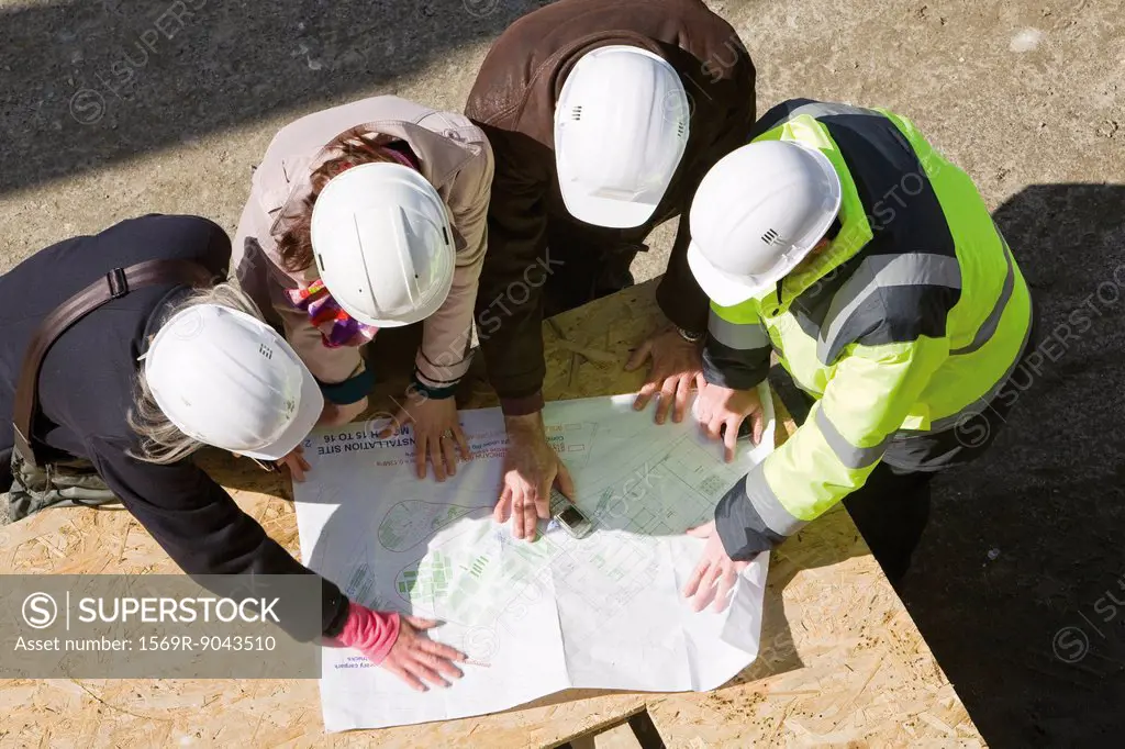 Architects meeting with building contractor at construction site to review blueprints