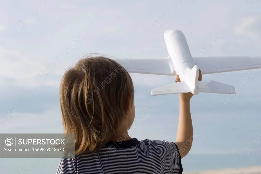 Child playing with toy airplane, rear view