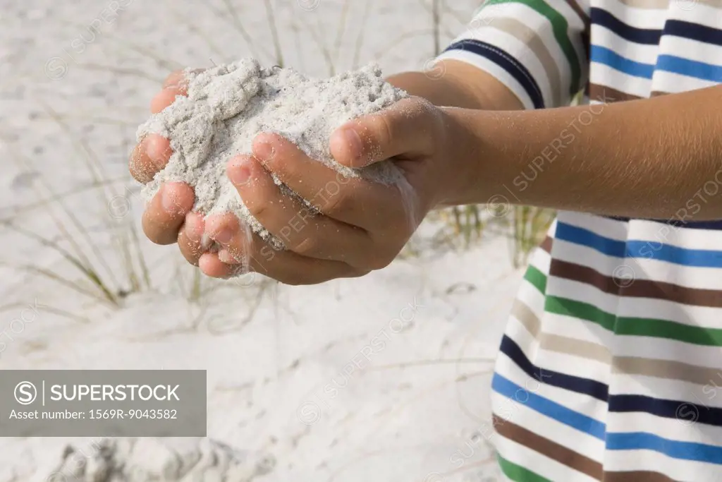Child scooping sand with hands