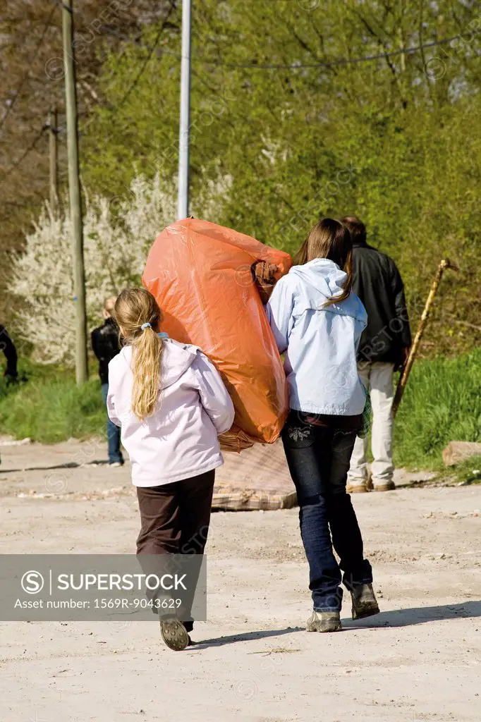 Girls carrying garbage bag together