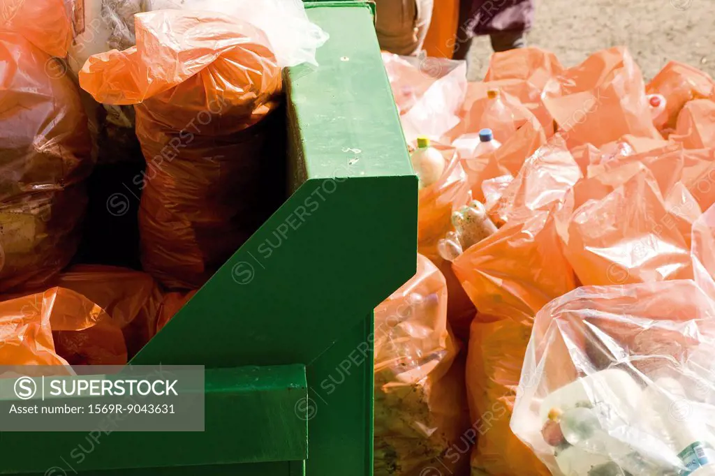 Garbage bags beside full dumpster