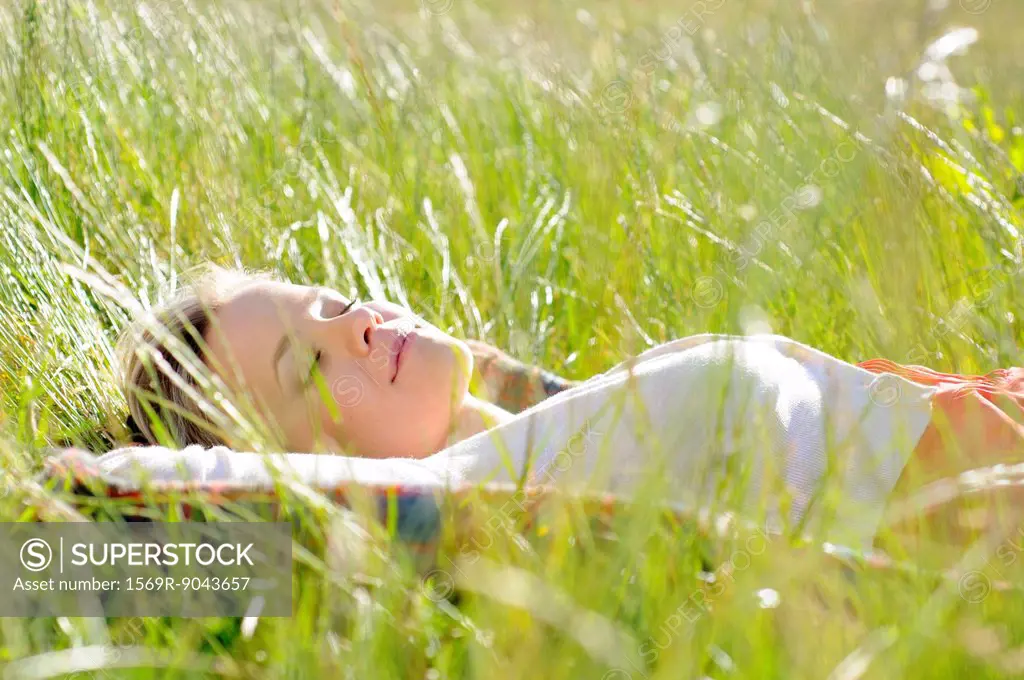 Young woman napping in tall grass
