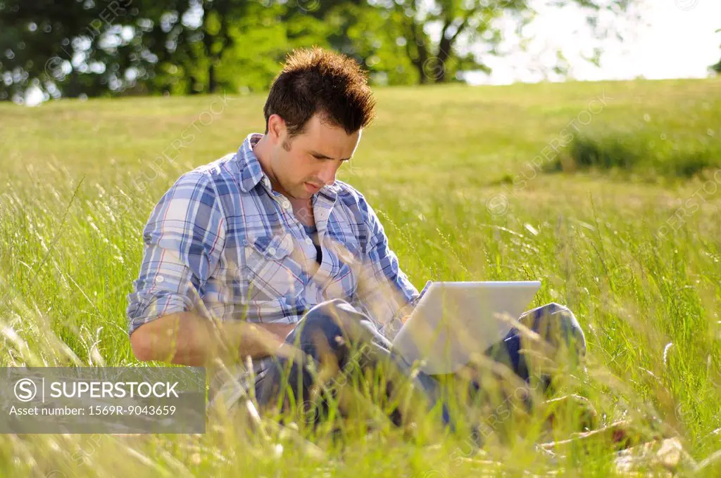 Young man using laptop computer in park