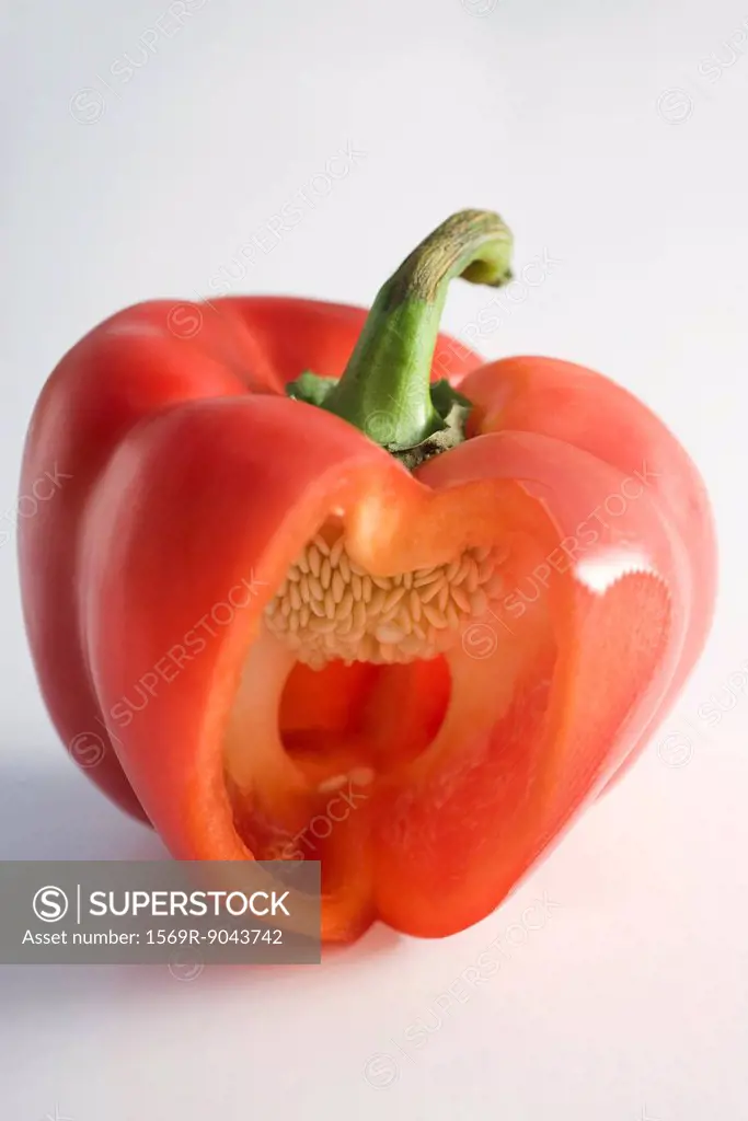 Red bell pepper with section cut out revealing tiny white seeds within
