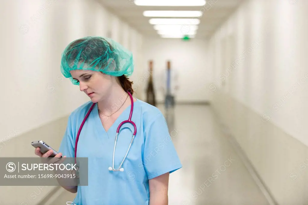 Nurse in hospital corridor using cell phone