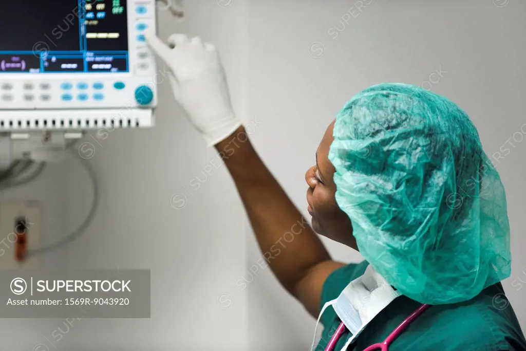 Healthcare worker changing settings on medical equipment monitor
