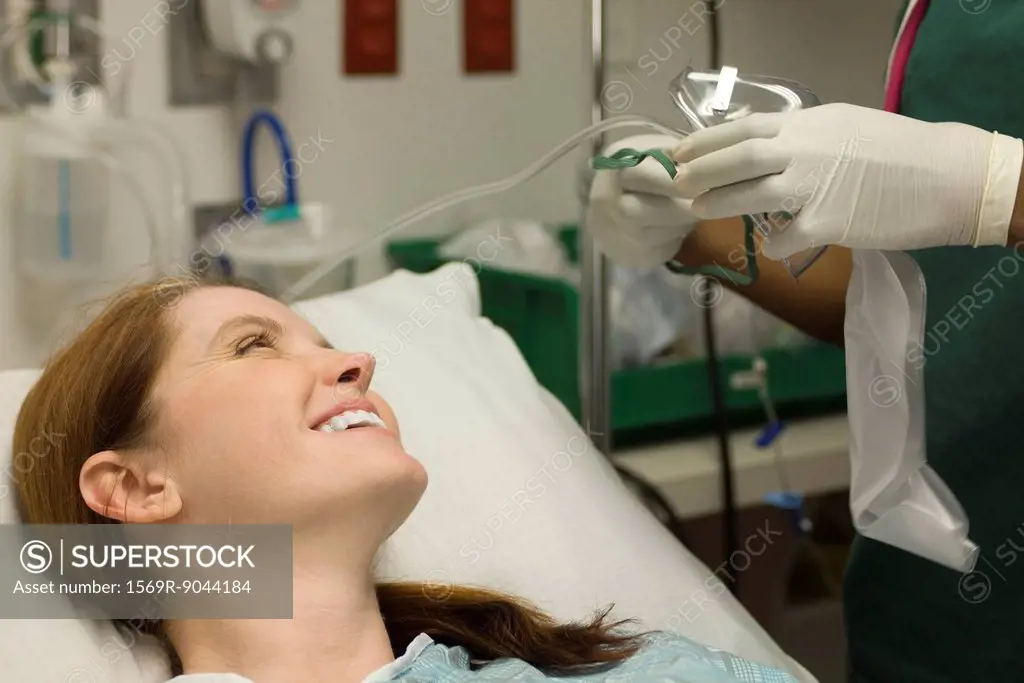 Female patient smiling as nurse prepares oxygen mask