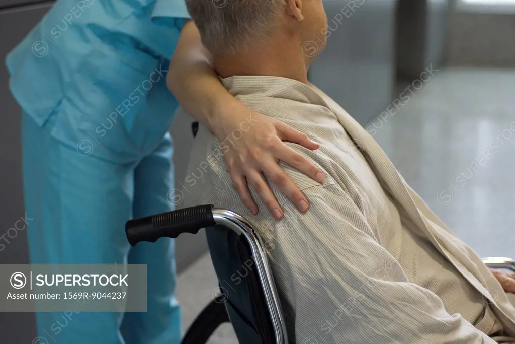 Nurse helping patient in wheelchair, cropped