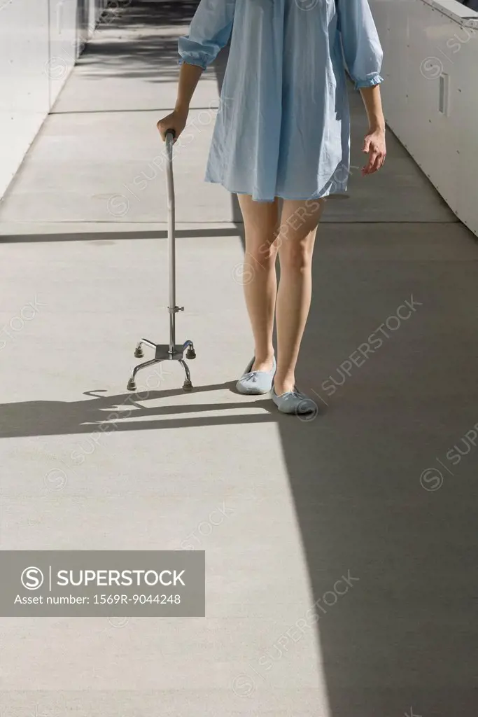 Recovering patient using cane to walk outdoors