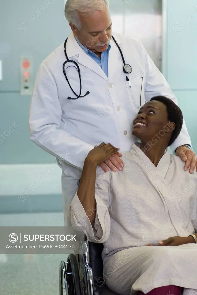 Doctor reassuring female patient in wheelchair